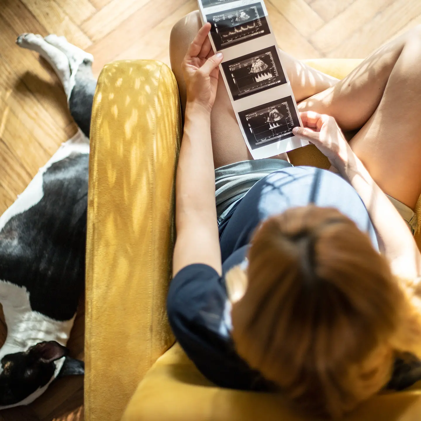Schwangere Frau betrachtet Ultraschallbilder ihres Babys
