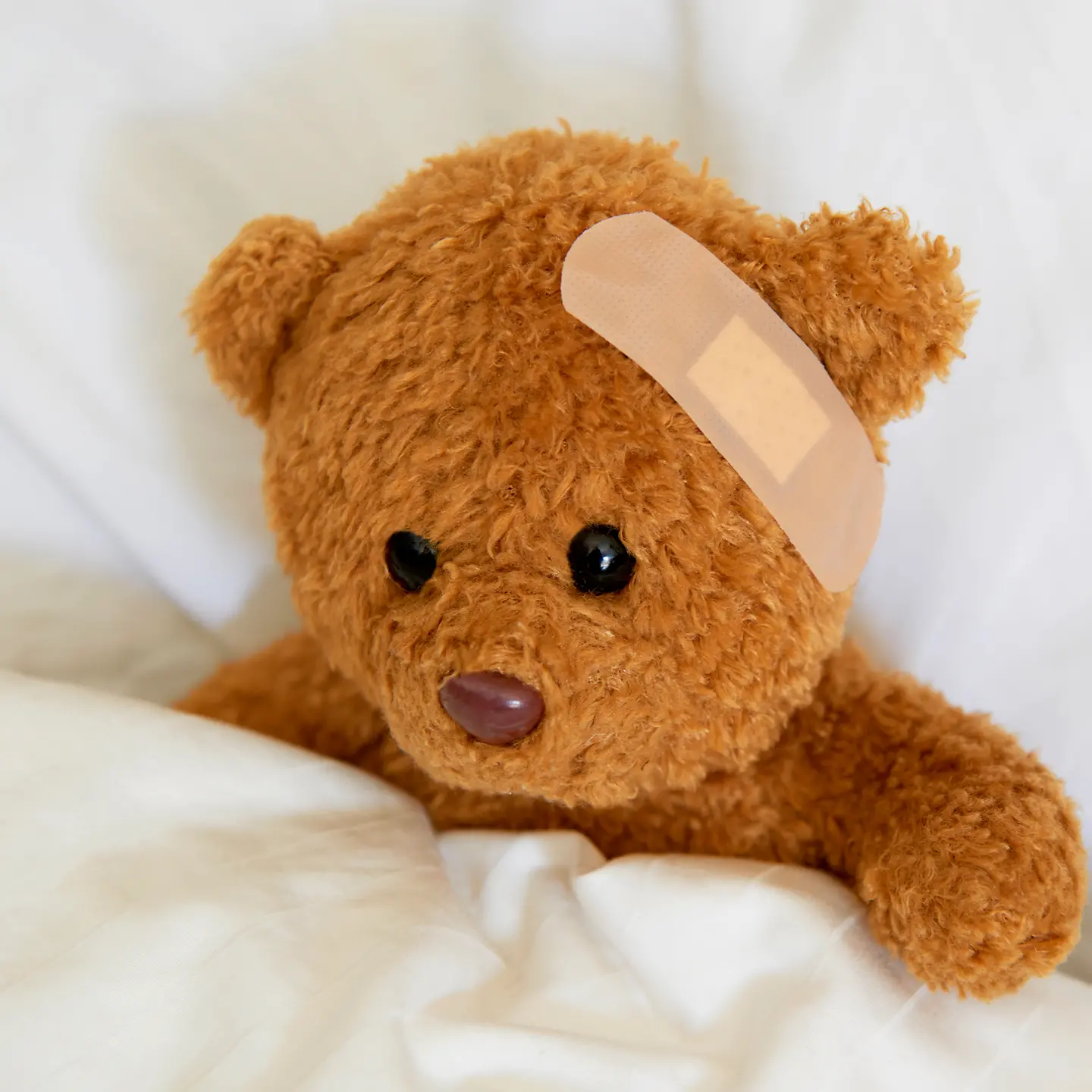 Teddy mit Pflaster im Krankenbett