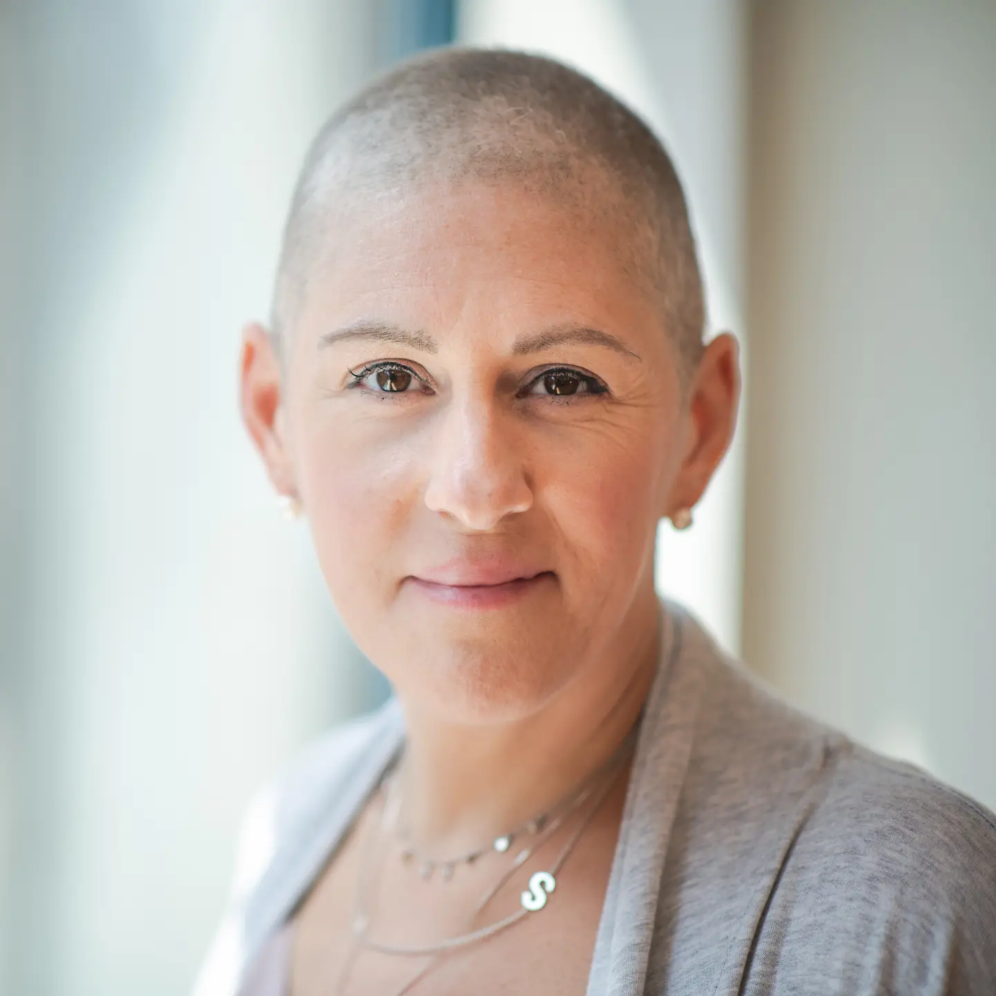 Eine an Krebs erkrankte Frau schaut lächelnd in die Kamera