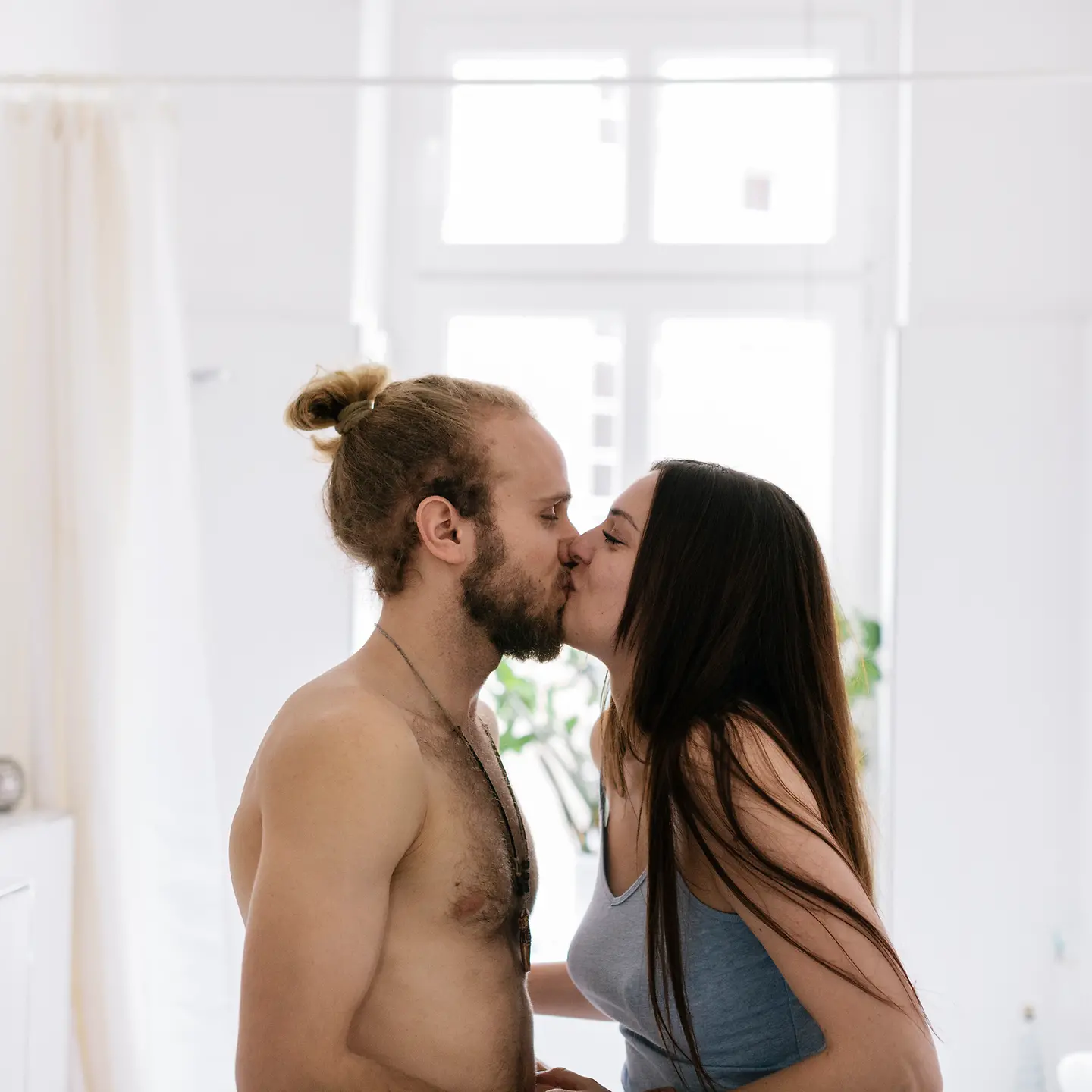Ein junges Paar küsst sich im Badezimmer. 