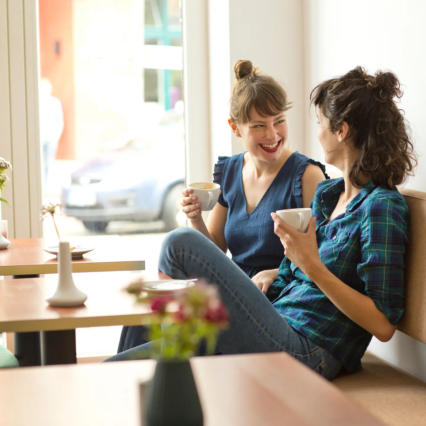 Zwei junge Frauen sitzen ganz entspannt bei einem Kaffee und unterhalten sich