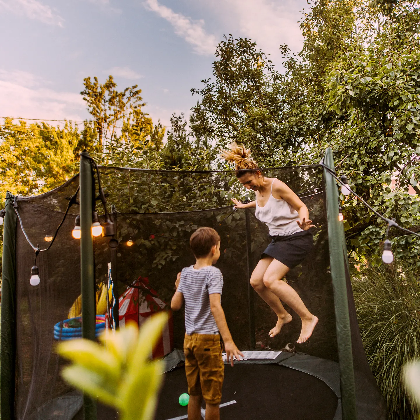 Eine Mutter und ihr Sohn springen auf einem Trampolin im Garten