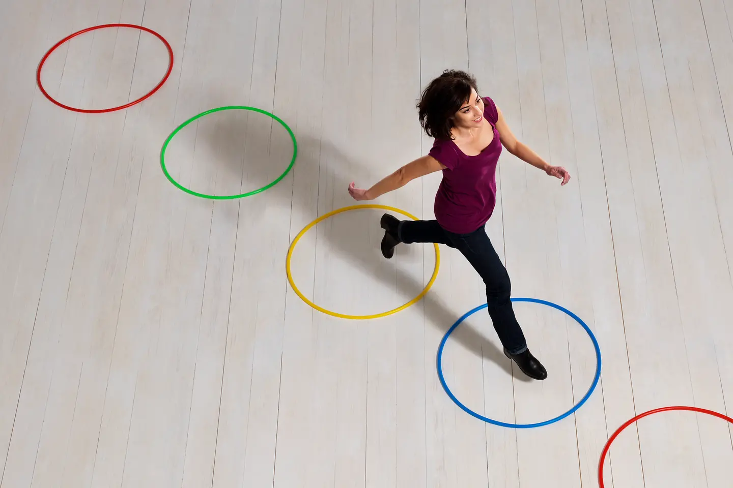 Junge Frau läuft konzentriert durch fünf olympische Ringe