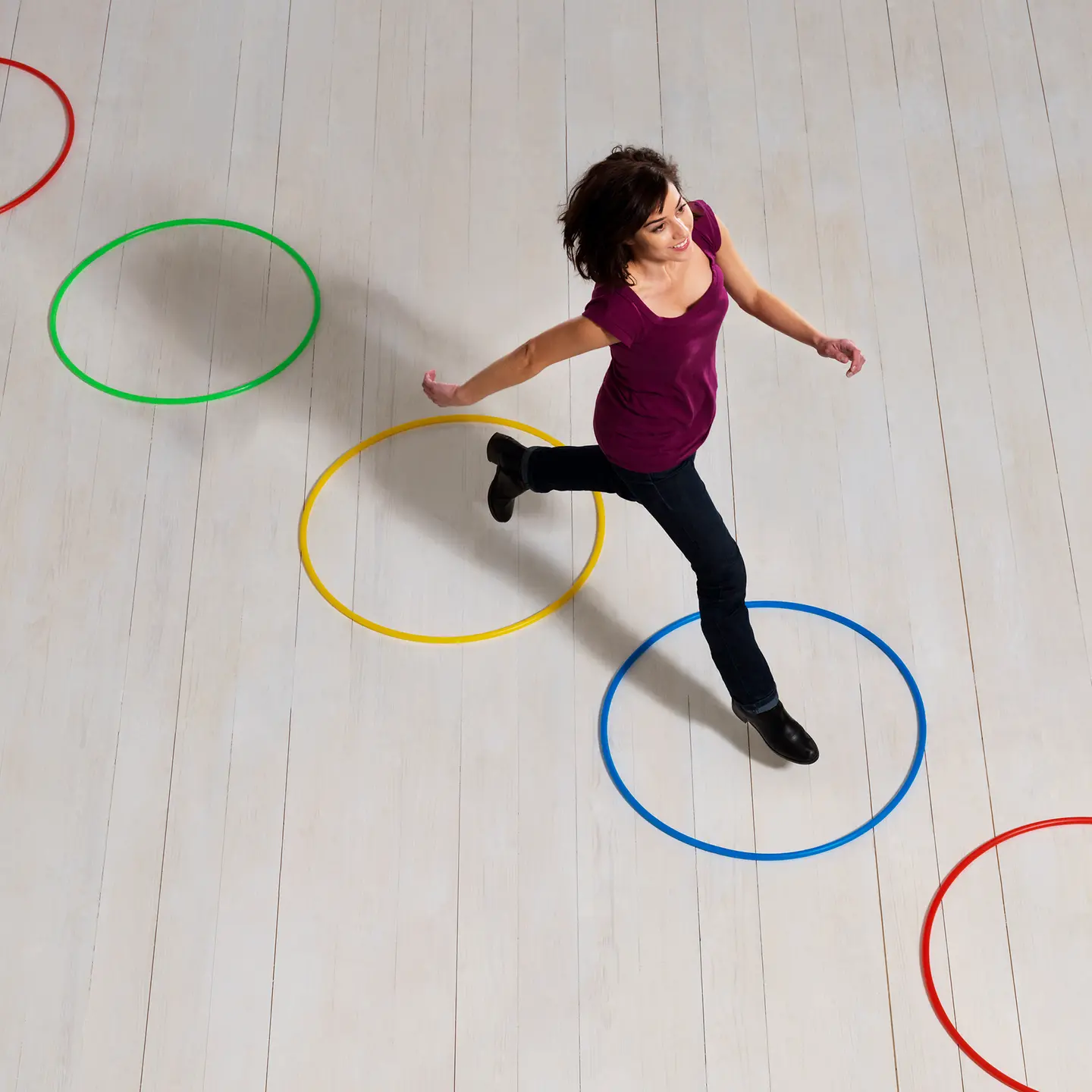 Junge Frau läuft konzentriert durch fünf olympische Ringe