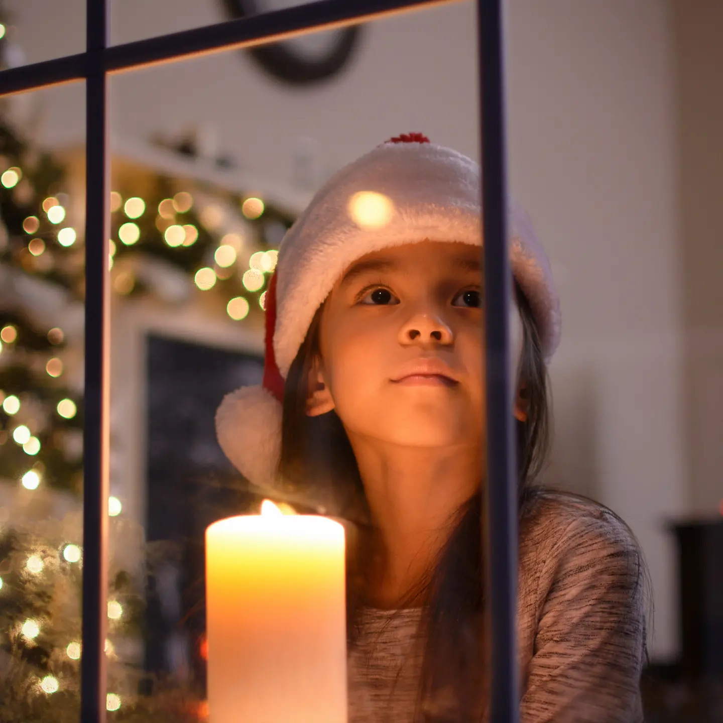Kleines Mädchen hat eine Nikolausmütze auf und schaut aus dem Fenster
