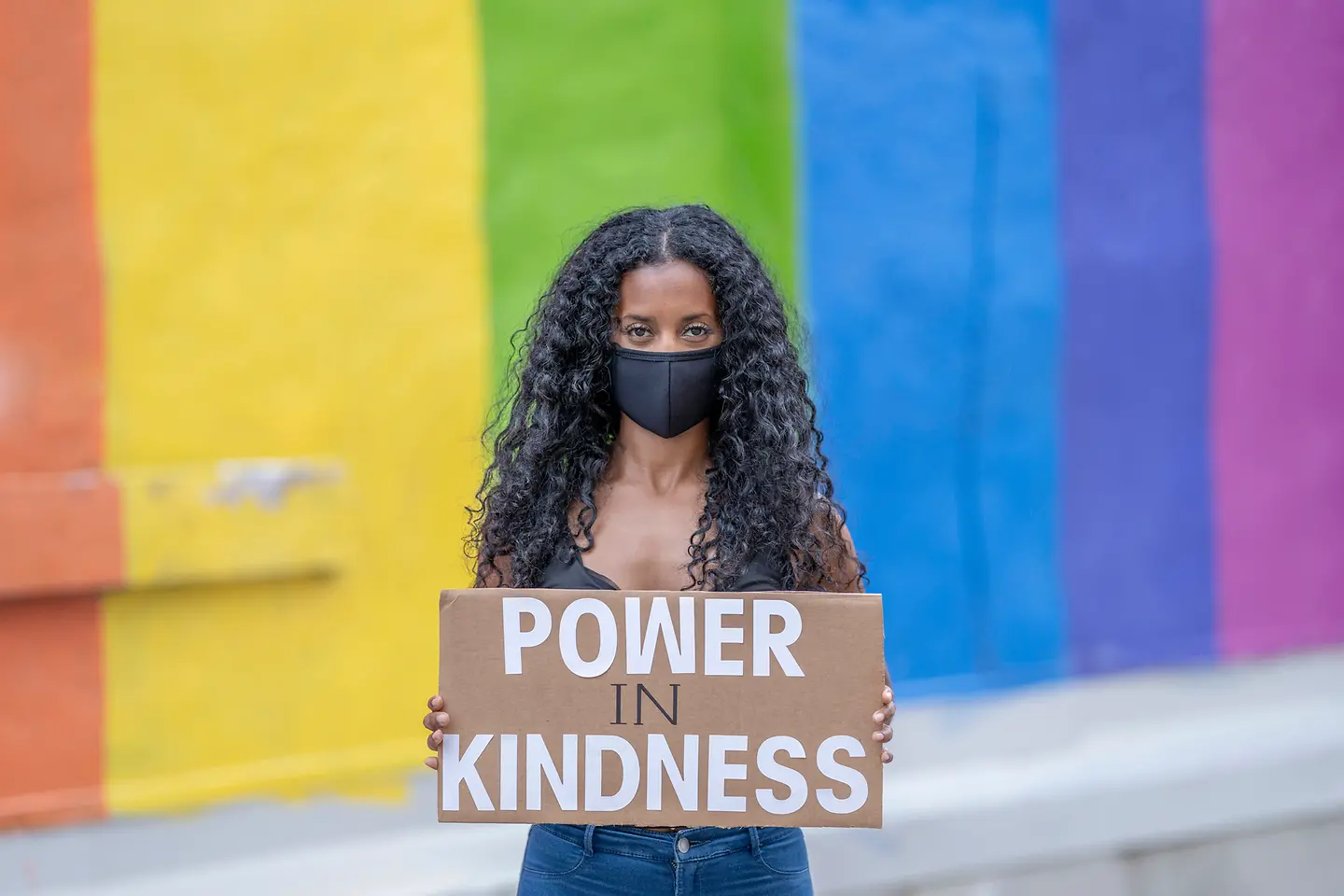 Demonstrantin vor einer bunten Wand hält ein Transparent