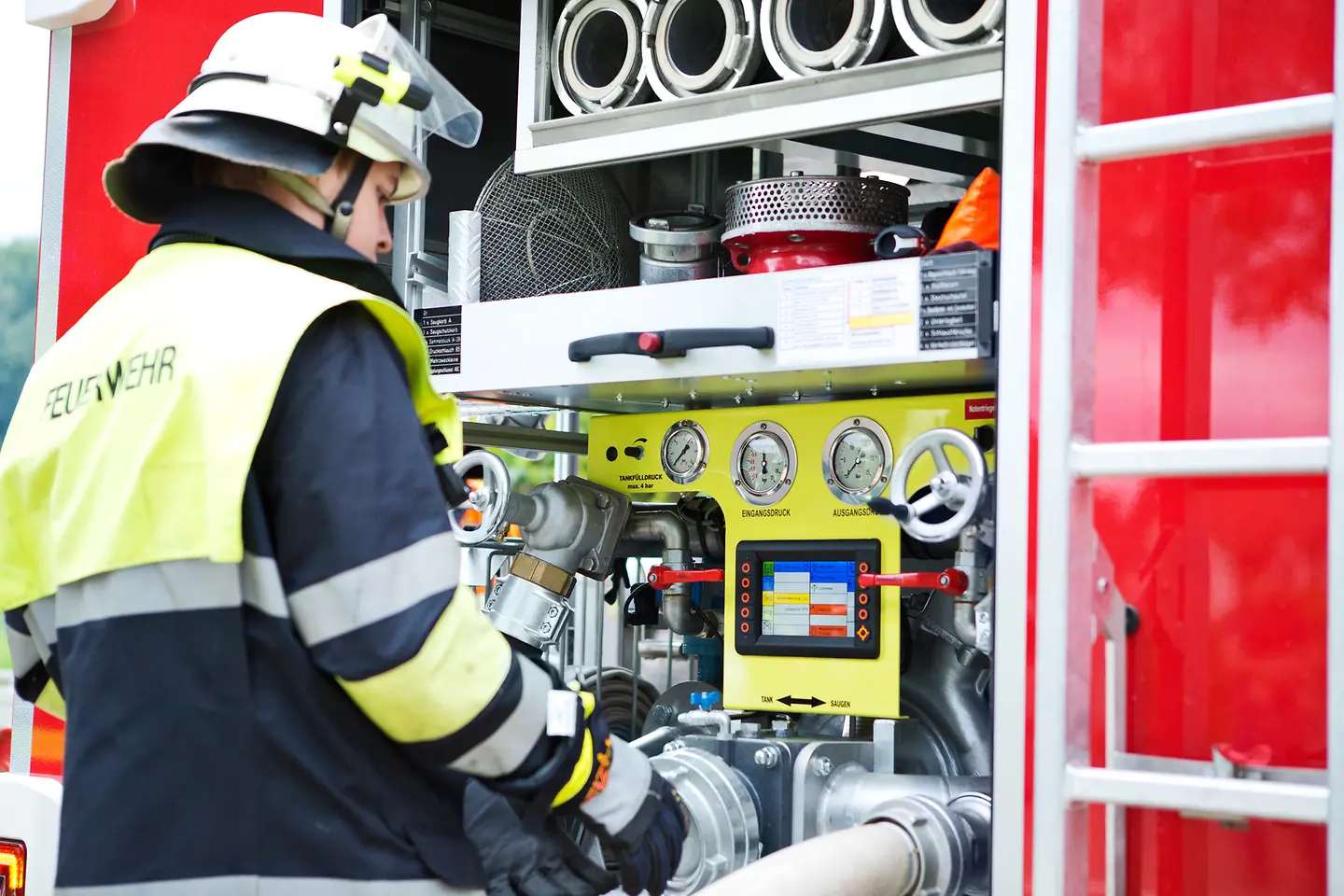 Feuerwehrmann in Ausrüstung am Schlauchwagen