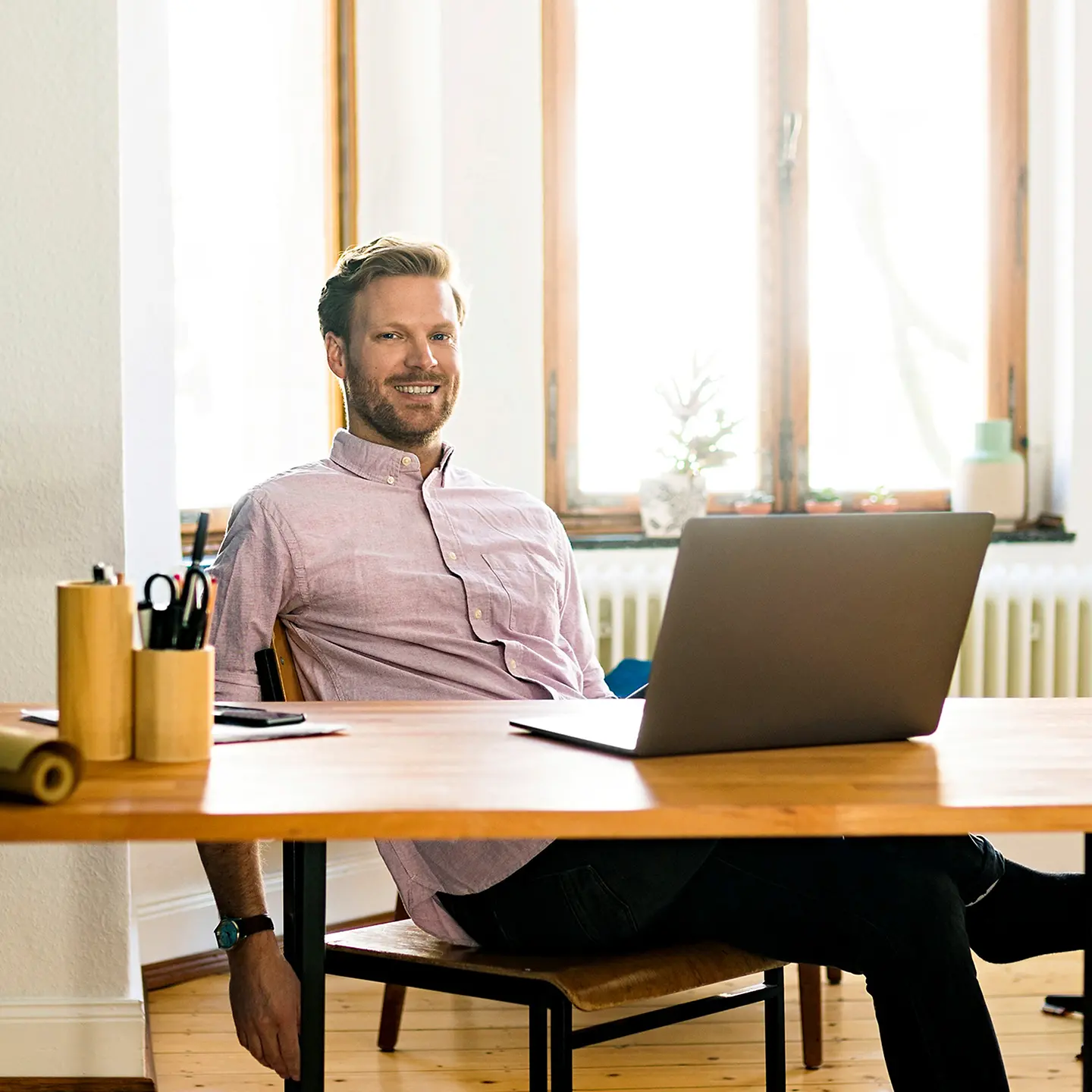 Ein Mann sitzt entspannt zuhause vor dem Schreibtisch