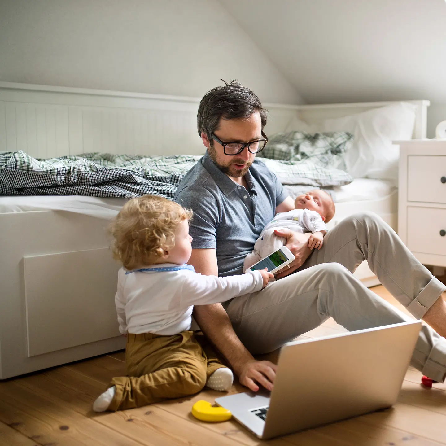 Mann mit zwei Kindern am Laptop auf dem Fußboden im Kinderzimmer