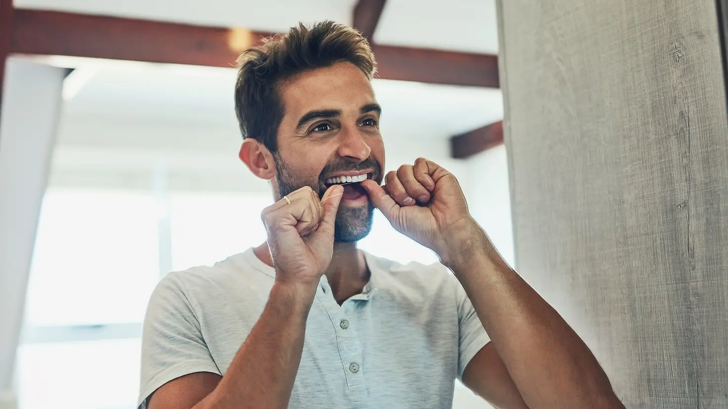 Ein Mann reinigt sich die Zähne mit Zahnseide