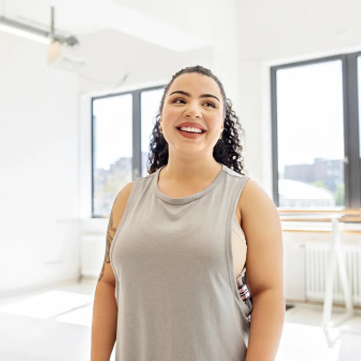 Eine mehrgewichtige junge Frau lächelt beim Fitnesskurs