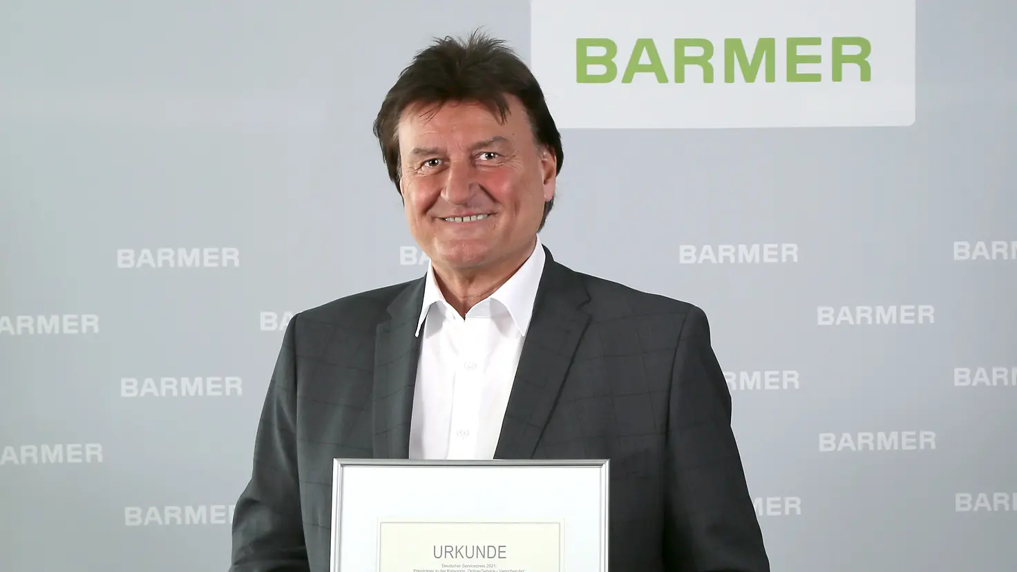 Der stellvertretende Vorstandsvorsitzende der Barmer, Jürgen Rothmaier, hält die Urkunde zum Deutschen Servicepreis 2021