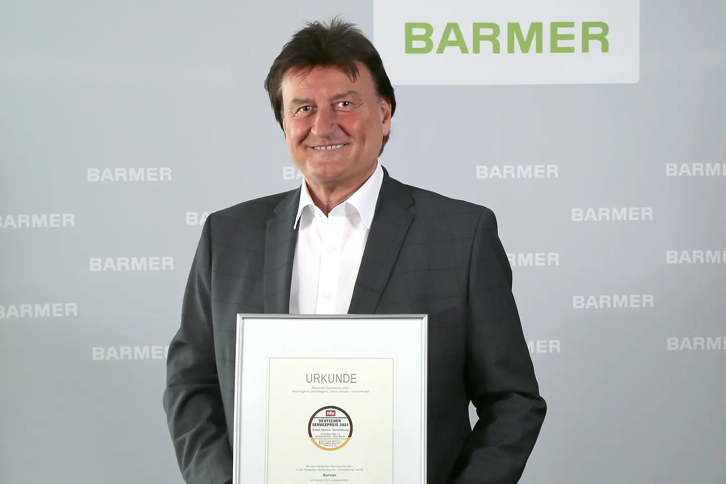 Der stellvertretende Vorstandsvorsitzende der Barmer, Jürgen Rothmaier, hält die Urkunde zum Deutschen Servicepreis 2021