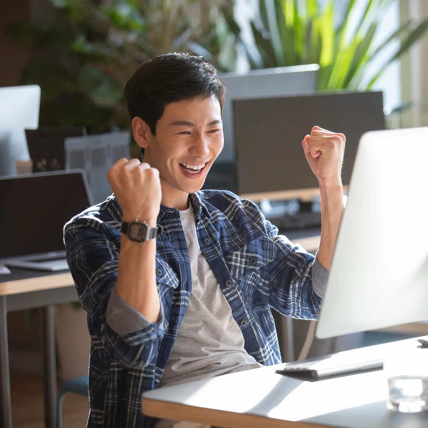 一位年轻的男士高兴地坐在电脑前