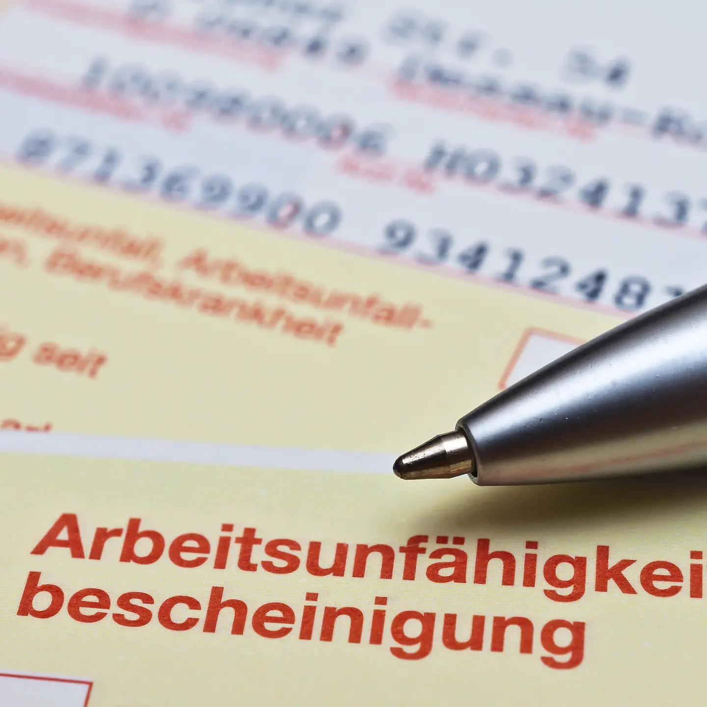 Blick auf eine Arbeitsunfähigkeitsbescheinigung (Krankschreibung) auf der ein Kugelschreiber liegt.