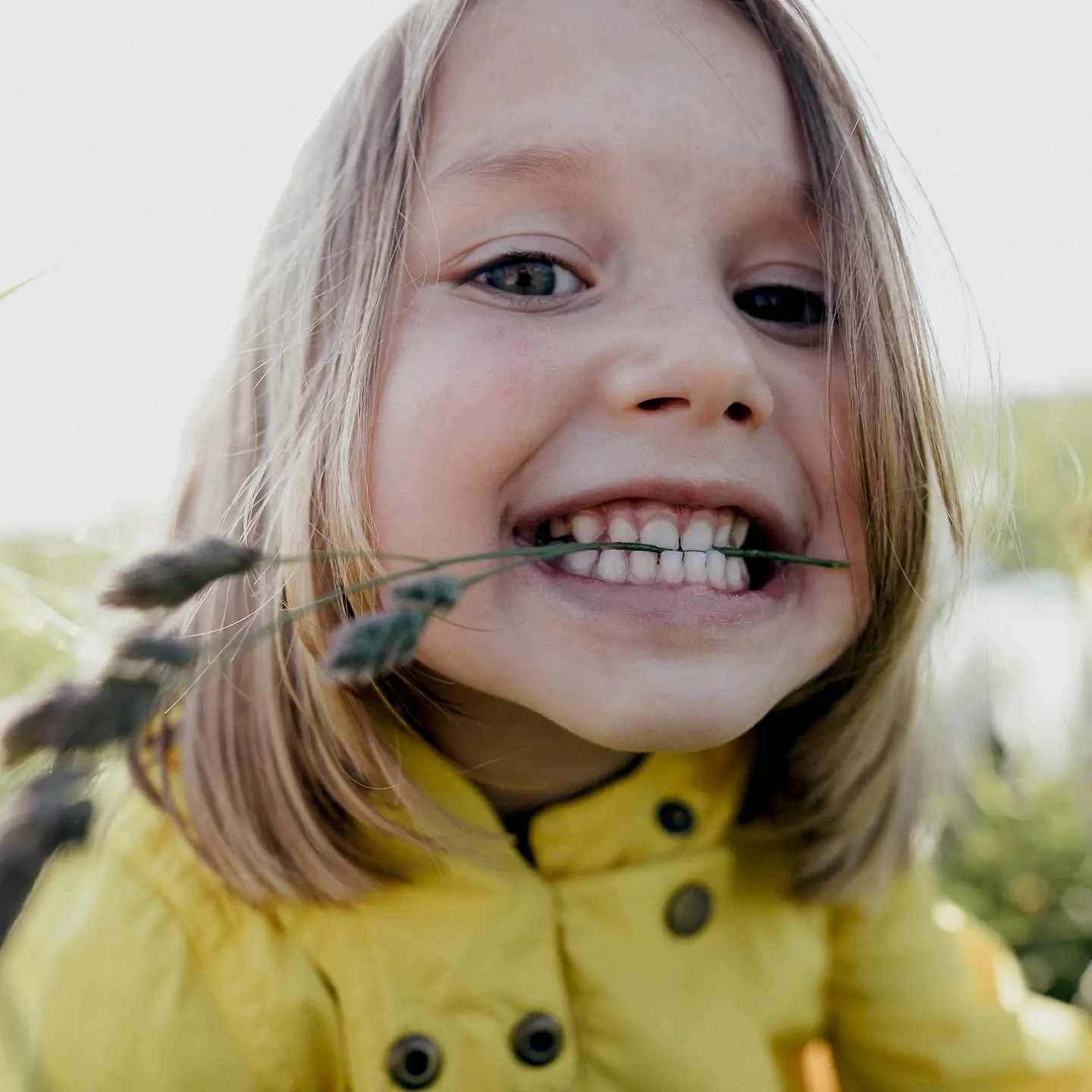 Mädchen mit Grashalm zwischen den Zähne