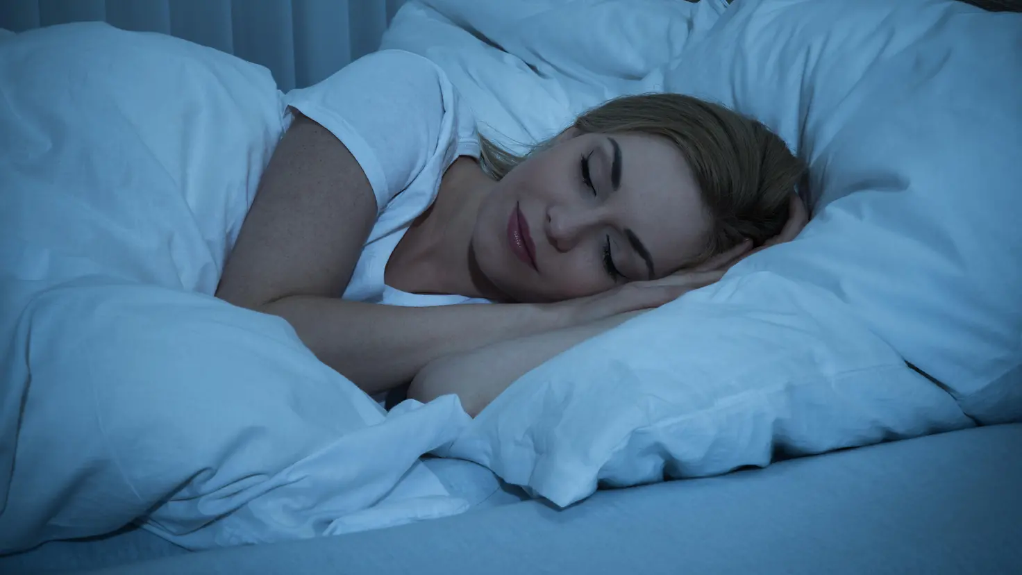 Eine Frau schläft friedlich mit einem Lächeln auf den Lippen im Bett