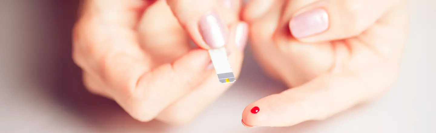Zwei Hände bei einer Blutzucker-Messung per Teststreifen