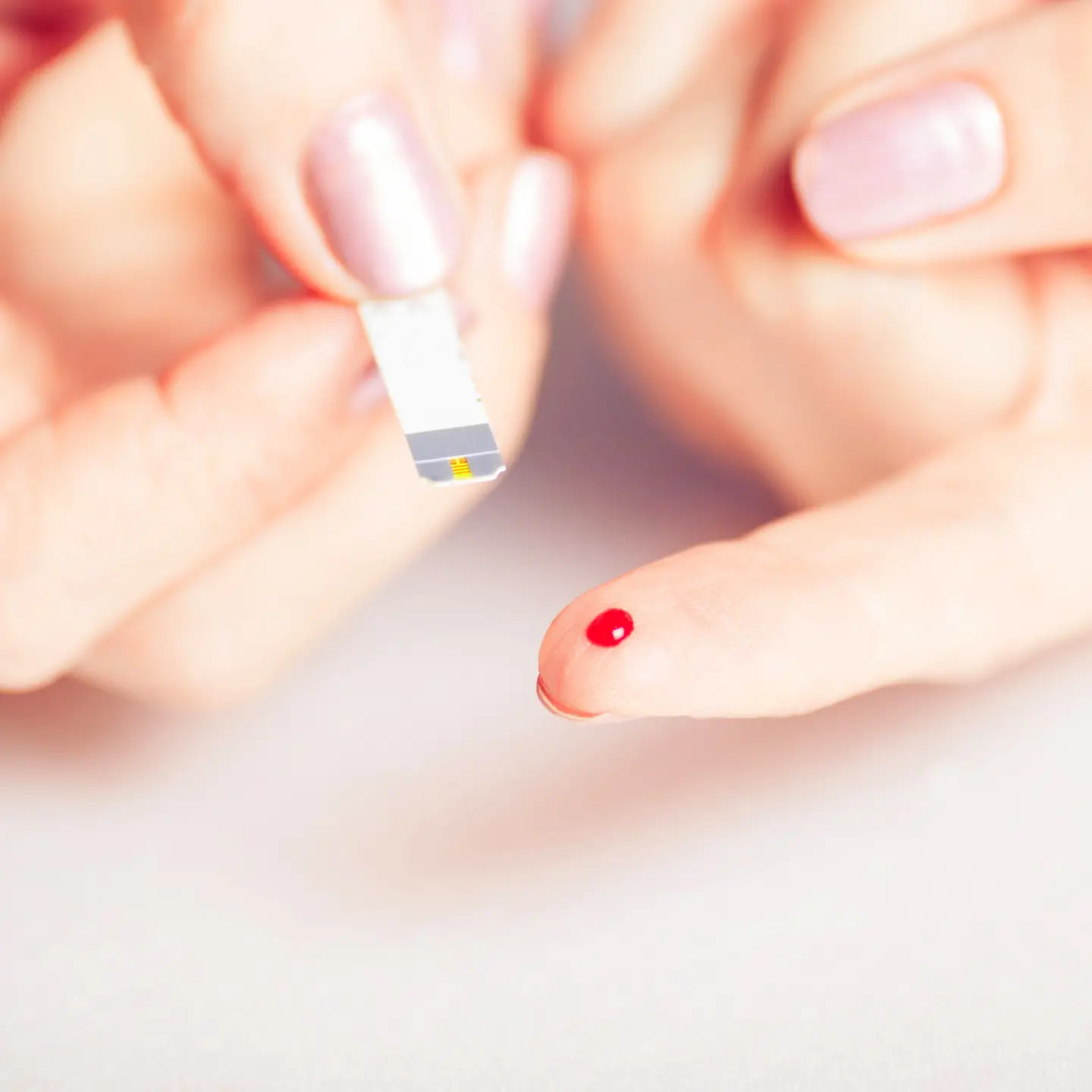 Zwei Hände bei einer Blutzucker-Messung per Teststreifen