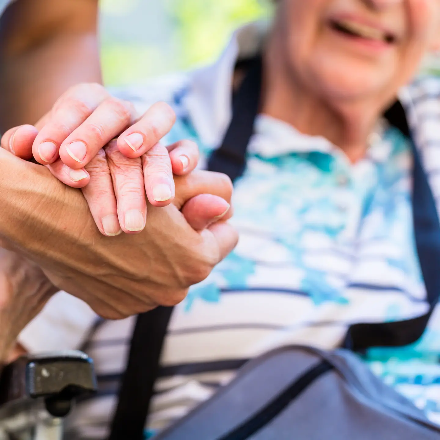 Eine Pflegekraft hält einer alten Person die Hand