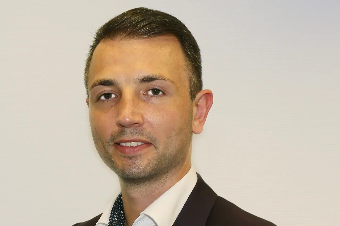 Benjamin Westerhoff; ein junger Mann mit braunen Haaren, schwarzen Sakko und weißen Hemd schaut in die Kamera.