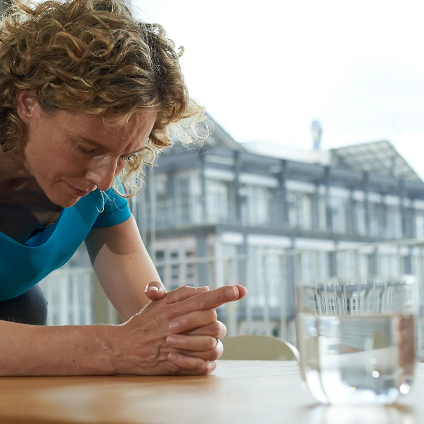Eine Frau sitzt vor einem Glas Wasser
