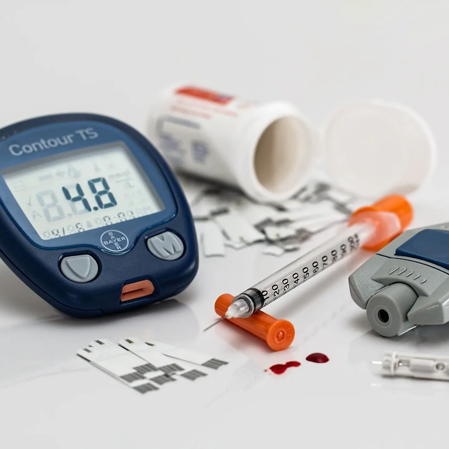Auf einem Tisch liegen ein Blutzuckermessgerät und Spritzbesteck für Diabetiker.