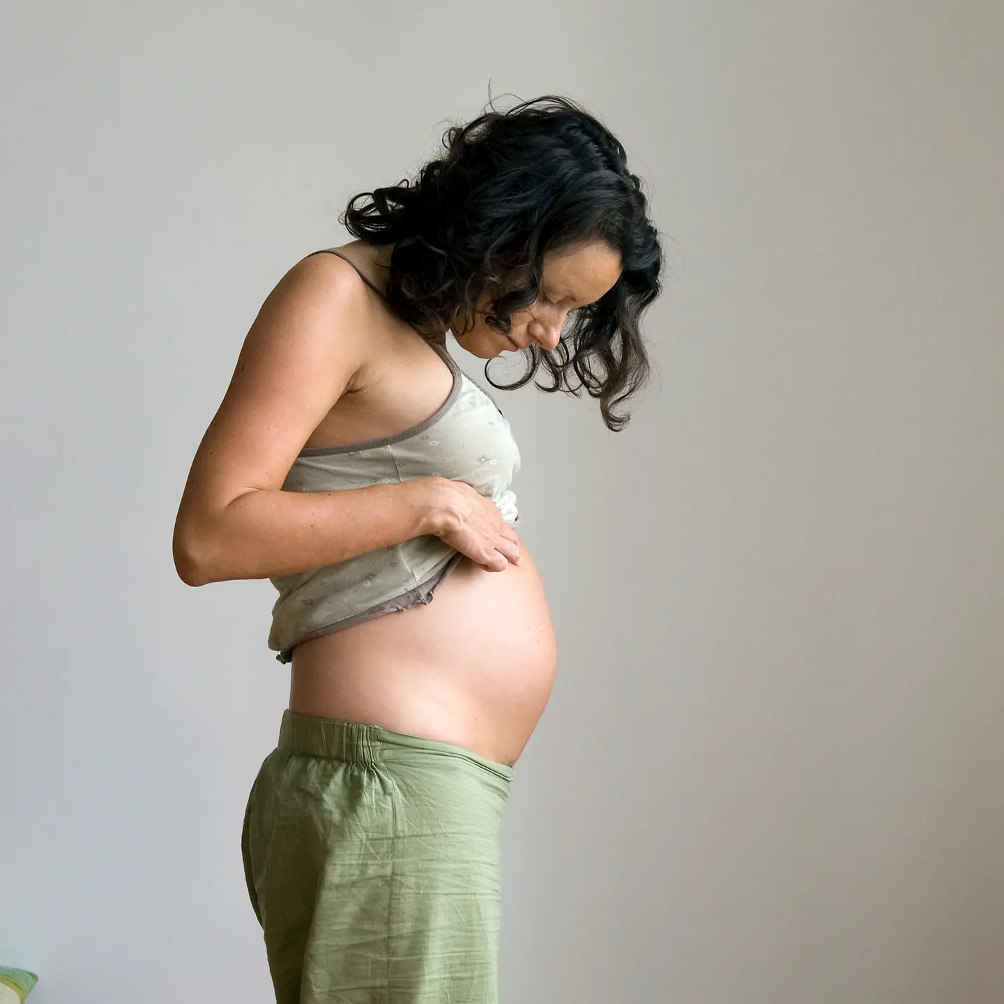 Junge Schwangere schaut auf ihren Bauch