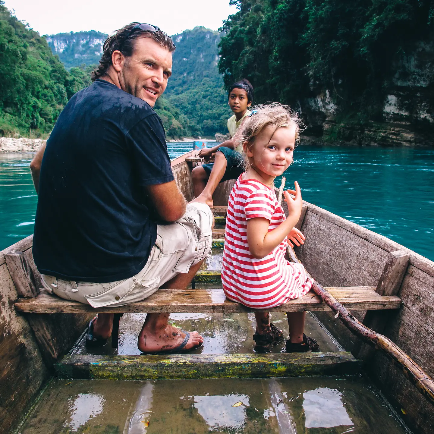 Ein Mann und ein kleines Mädchen fahren mit einem Holzboot auf einem Fluss