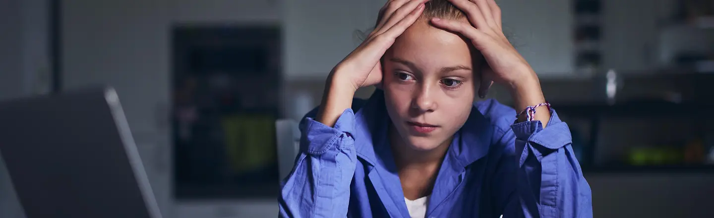 Ein Mädchen blickt traurig auf einen Computerbildschirm