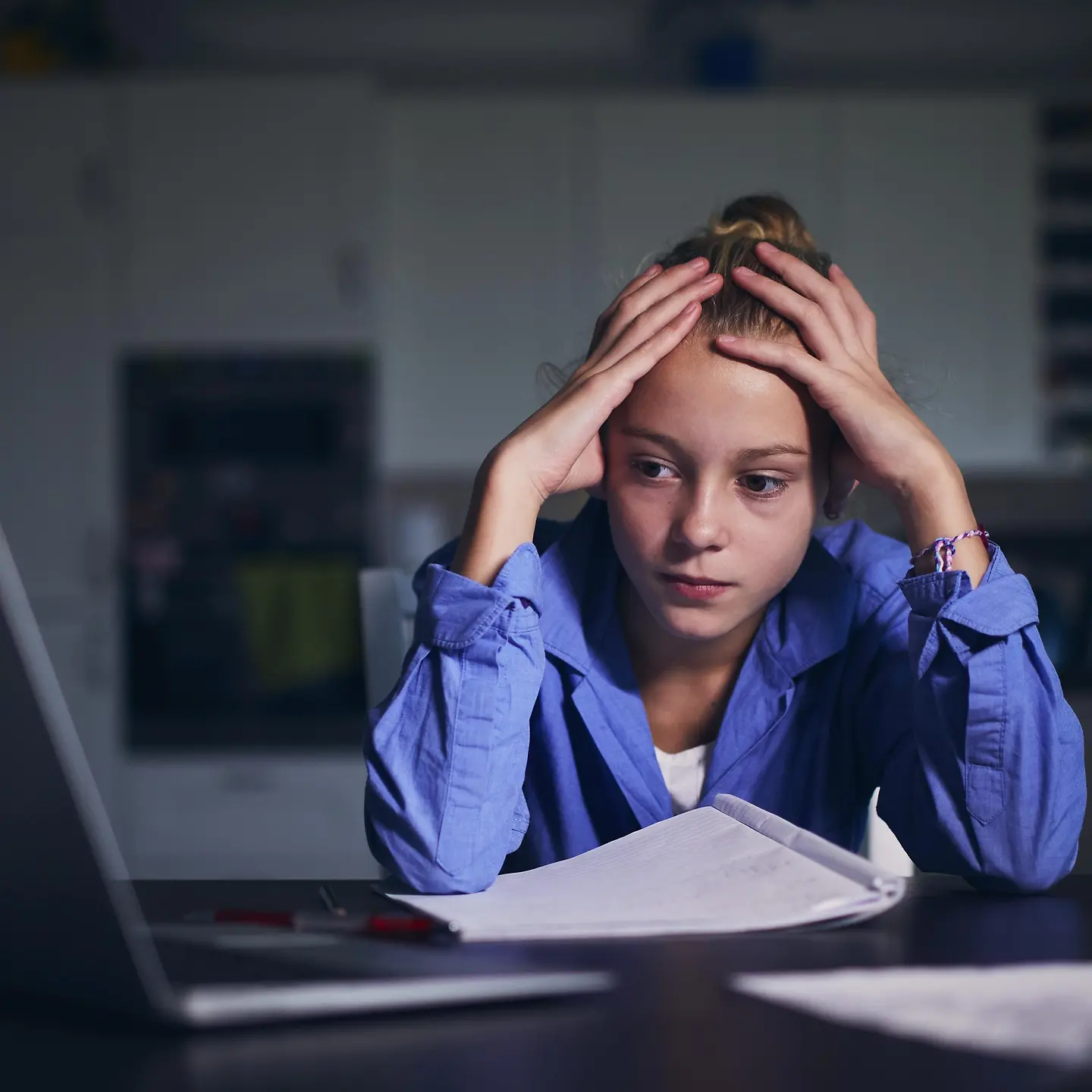Ein Mädchen blickt traurig auf einen Computerbildschirm