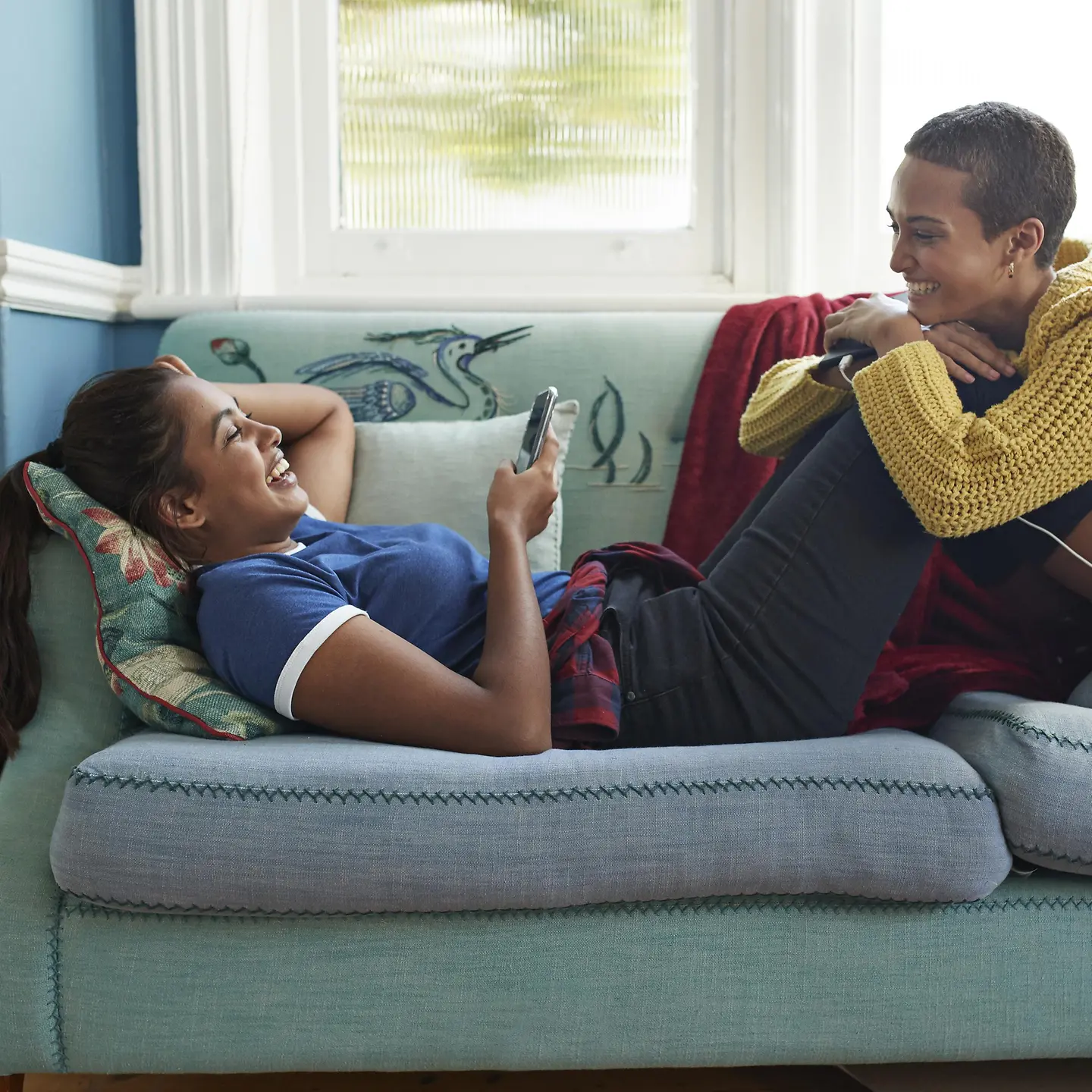 兩個年輕女子正在沙發上一起嬉戲。