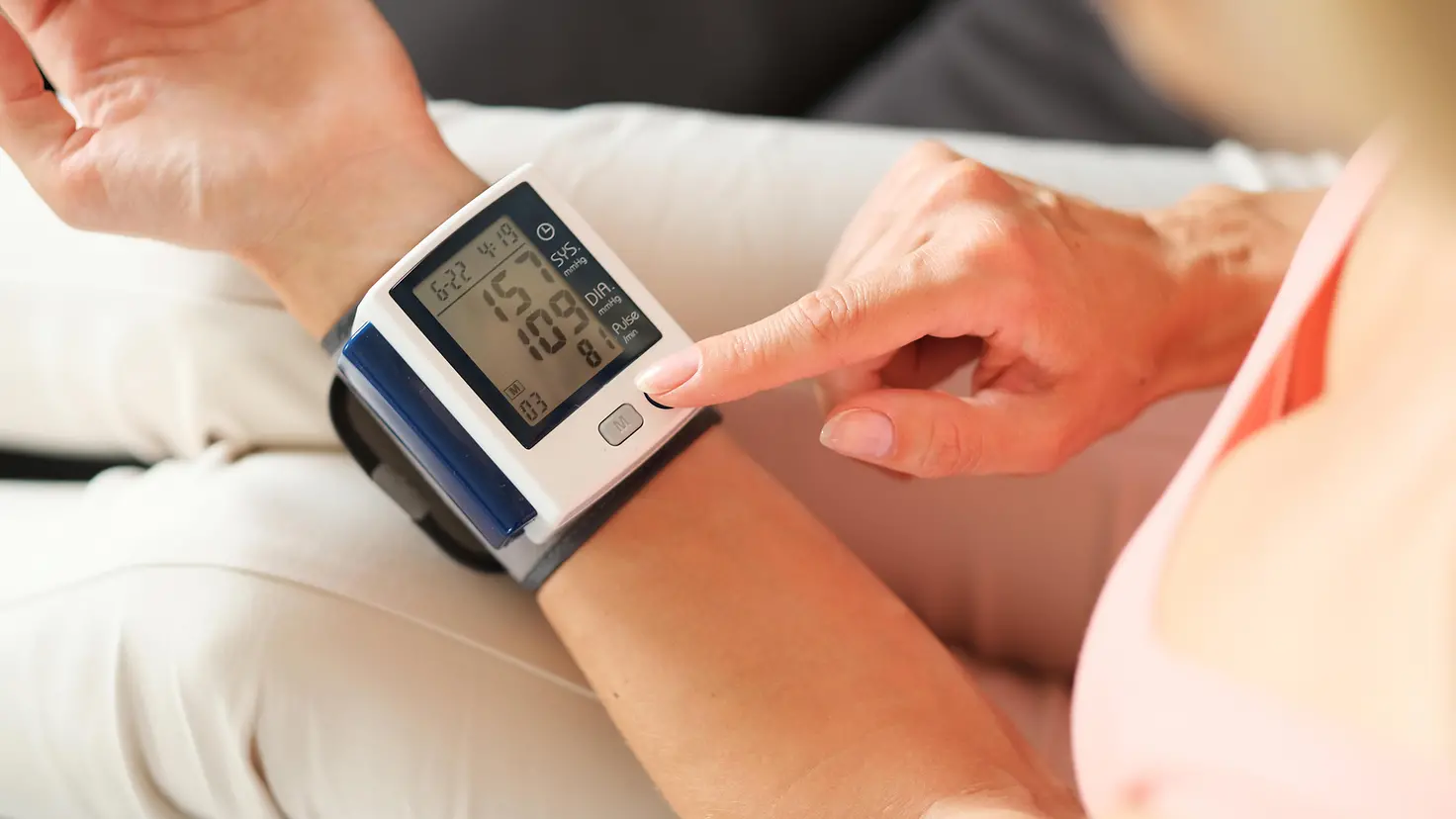 Ein Blutdruckmessgerät an einem Handgelenk einer Person zeigt die Blutdruckwerte an.