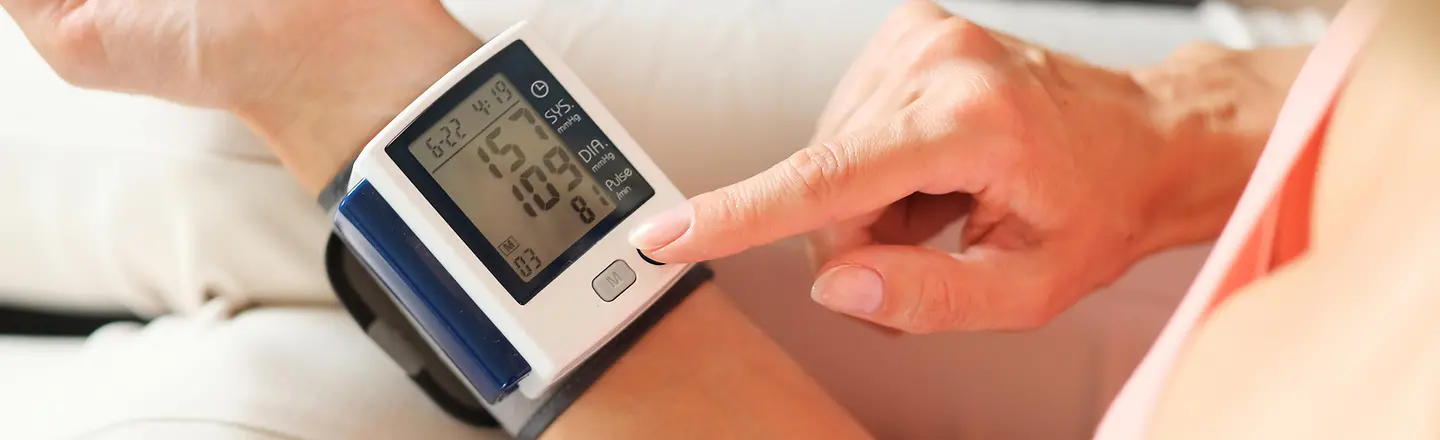 Ein Blutdruckmessgerät an einem Handgelenk einer Person zeigt die Blutdruckwerte an.