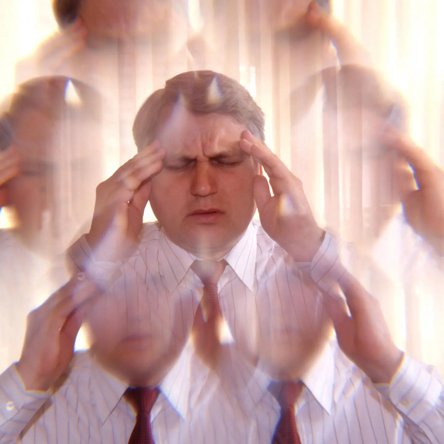 Ein Mann hält sich schmerzerfüllt mit beiden Händen den Kopf.