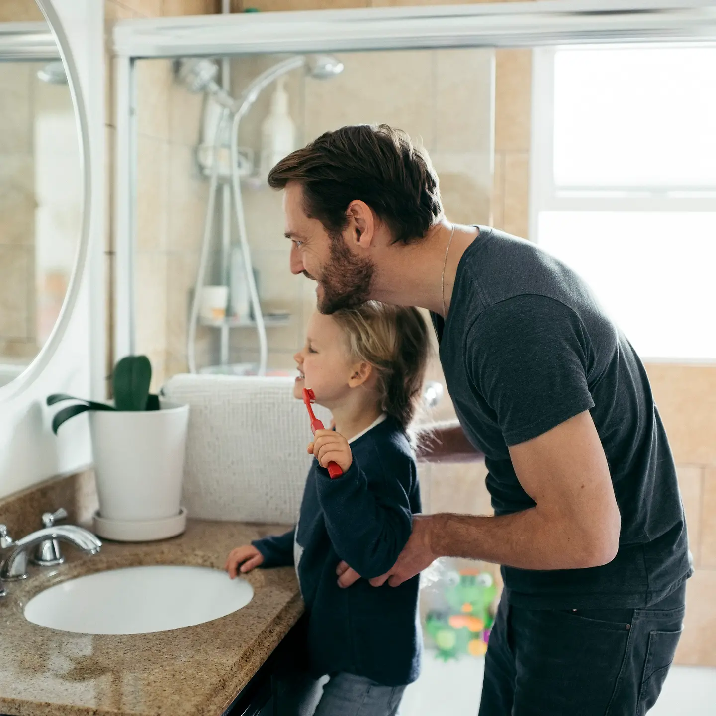 Vater und Tochter im Bad beim Zähne putzen