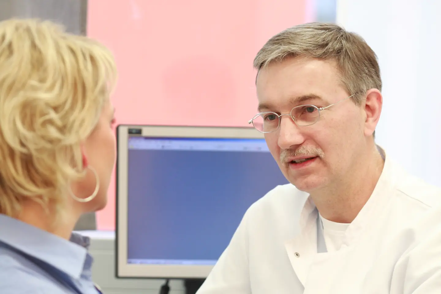 Ein Arzt und eine Patientin sitzen sich im Gespräch gegenüber