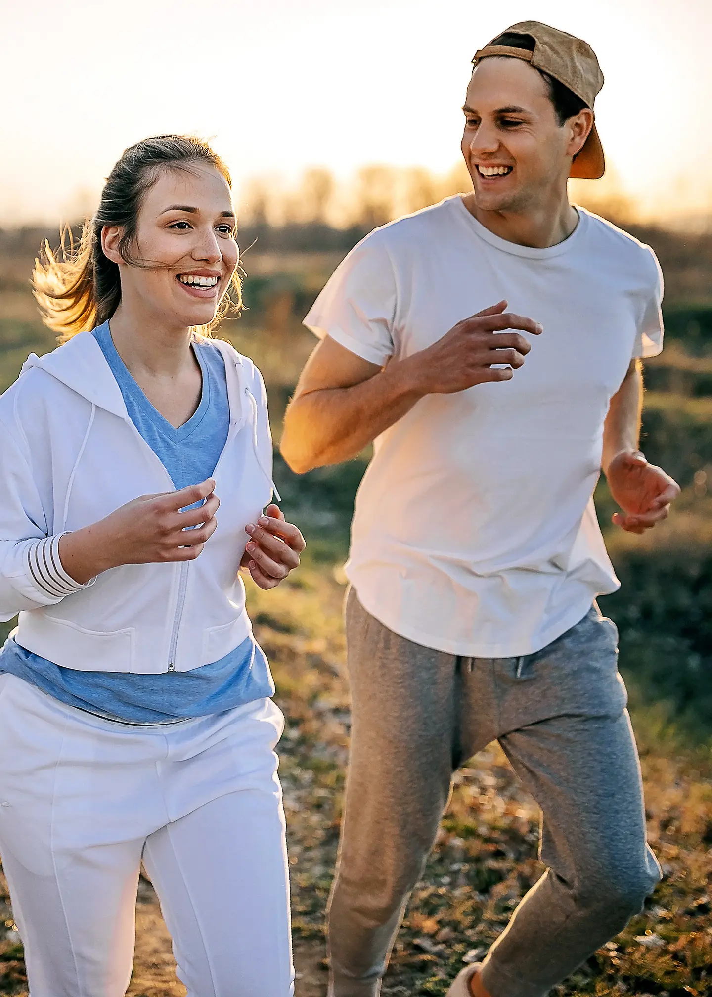 Ein junges Paar joggt über einen Feldweg. 