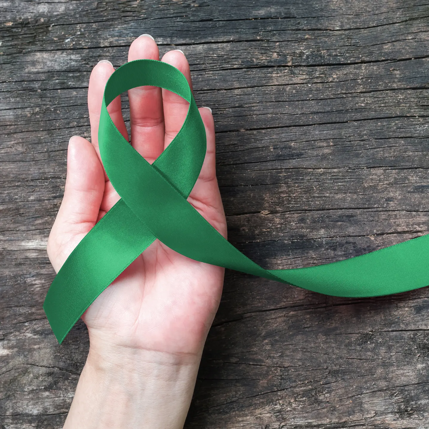 Eine Hand hält eine Schleife aus grünem Band