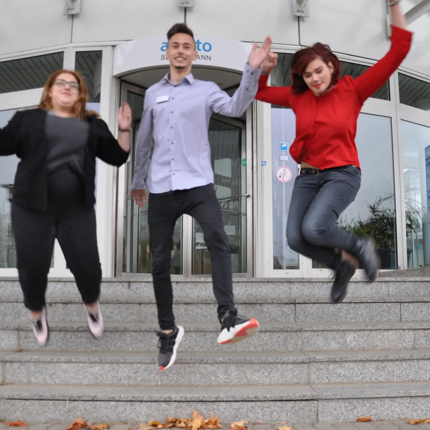 Drei Arvato-Azubis springen von der Treppe