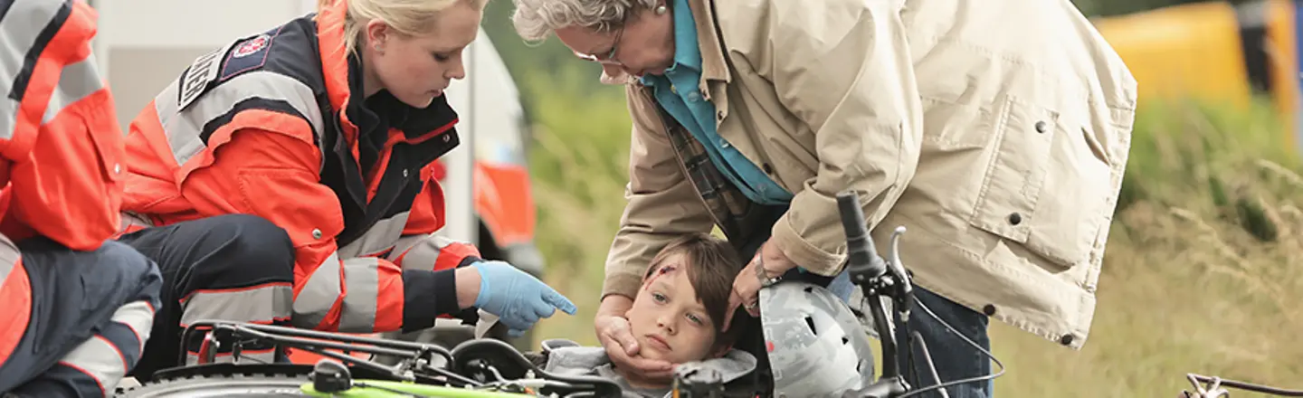 Johanniter-Unfall-Hilfe: Zwei Johanniter-Sanitäter simulieren mit einem Kind und einer Seniorin erste Hilfe bei einem Unfall.