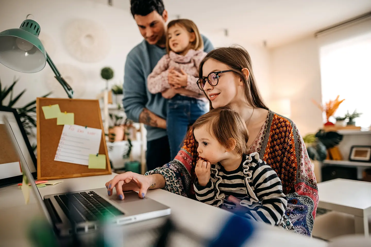 Eine junge Mutter mit Tochter am Schreibtisch mit Laptop