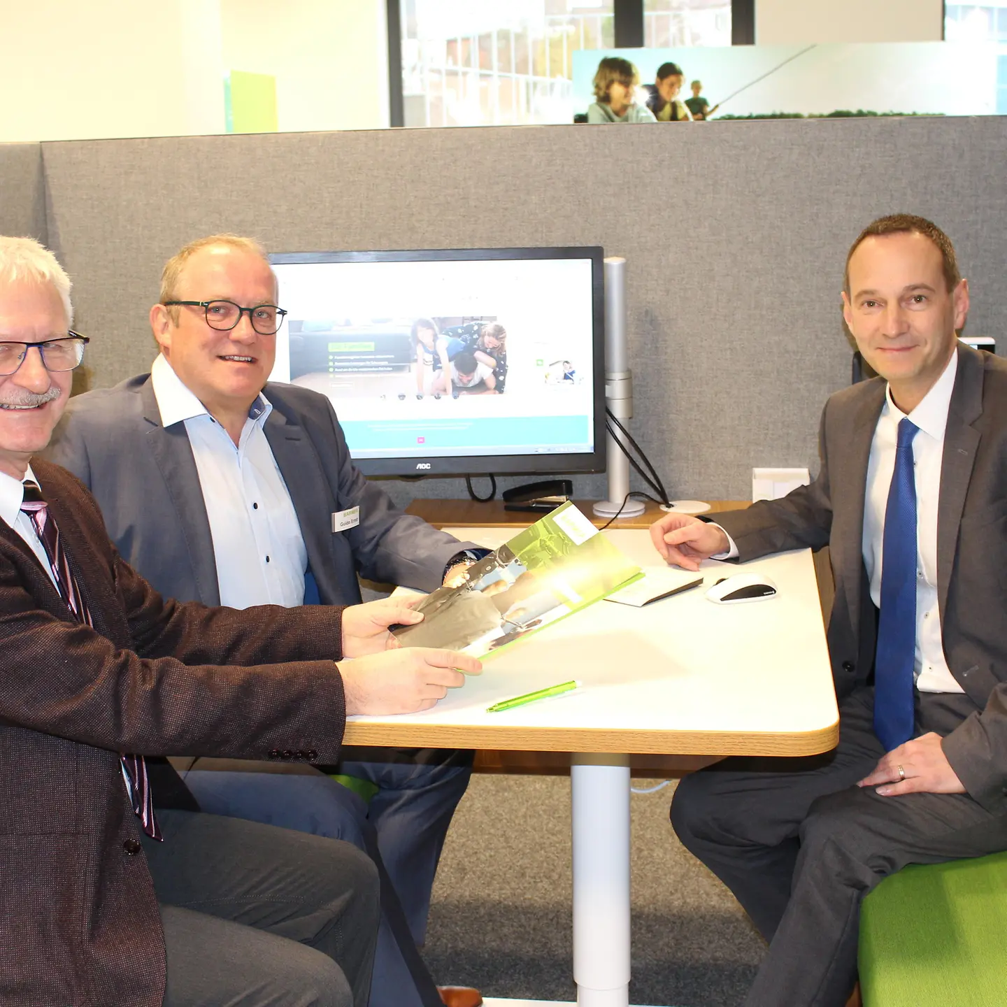 Der Bürgermeister von Illingen sowie Guido Ernst und Ulriche Jene von der BARMER sitzen in einer Beratungsbox.