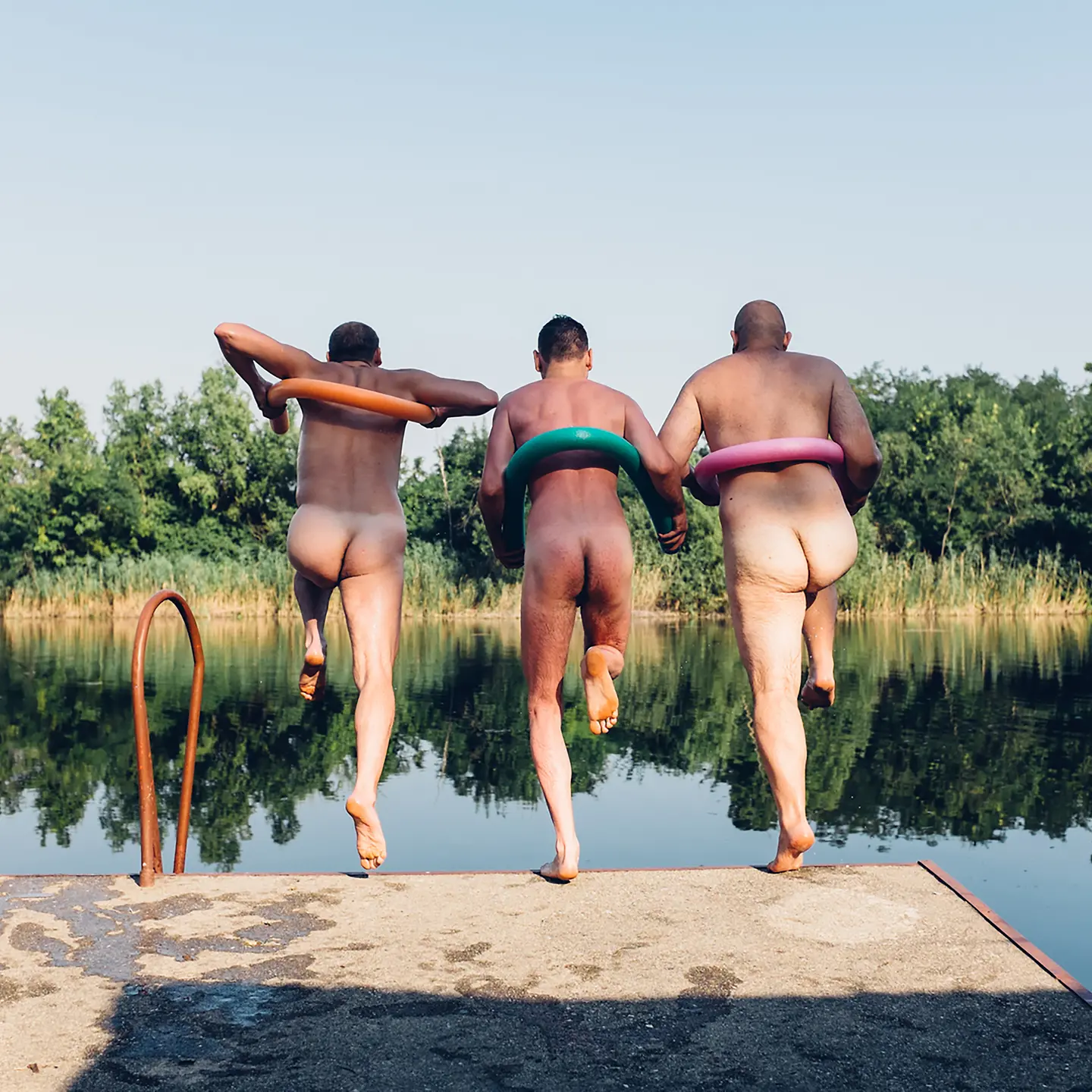 Drei Herren springen nackt in einen See