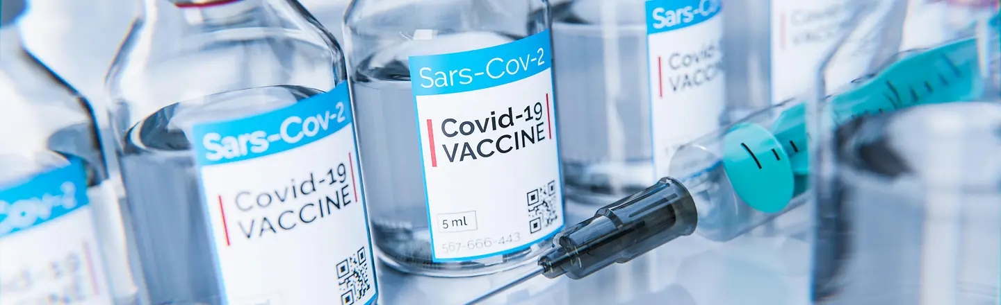 Das Bild zeigt Fläschchen mit Corona-Impfstoff neben einer Spritze.