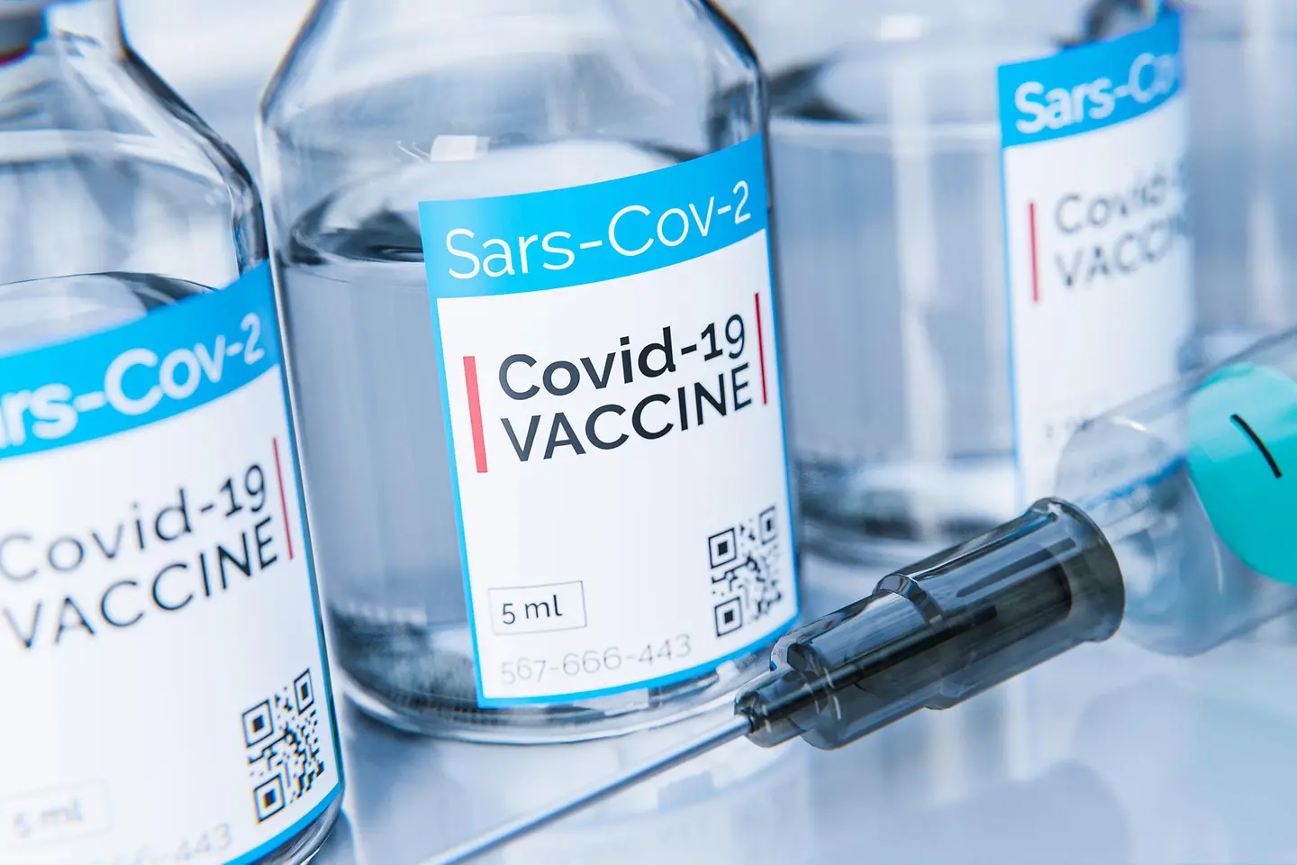 Das Bild zeigt Fläschchen mit Corona-Impfstoff neben einer Spritze.