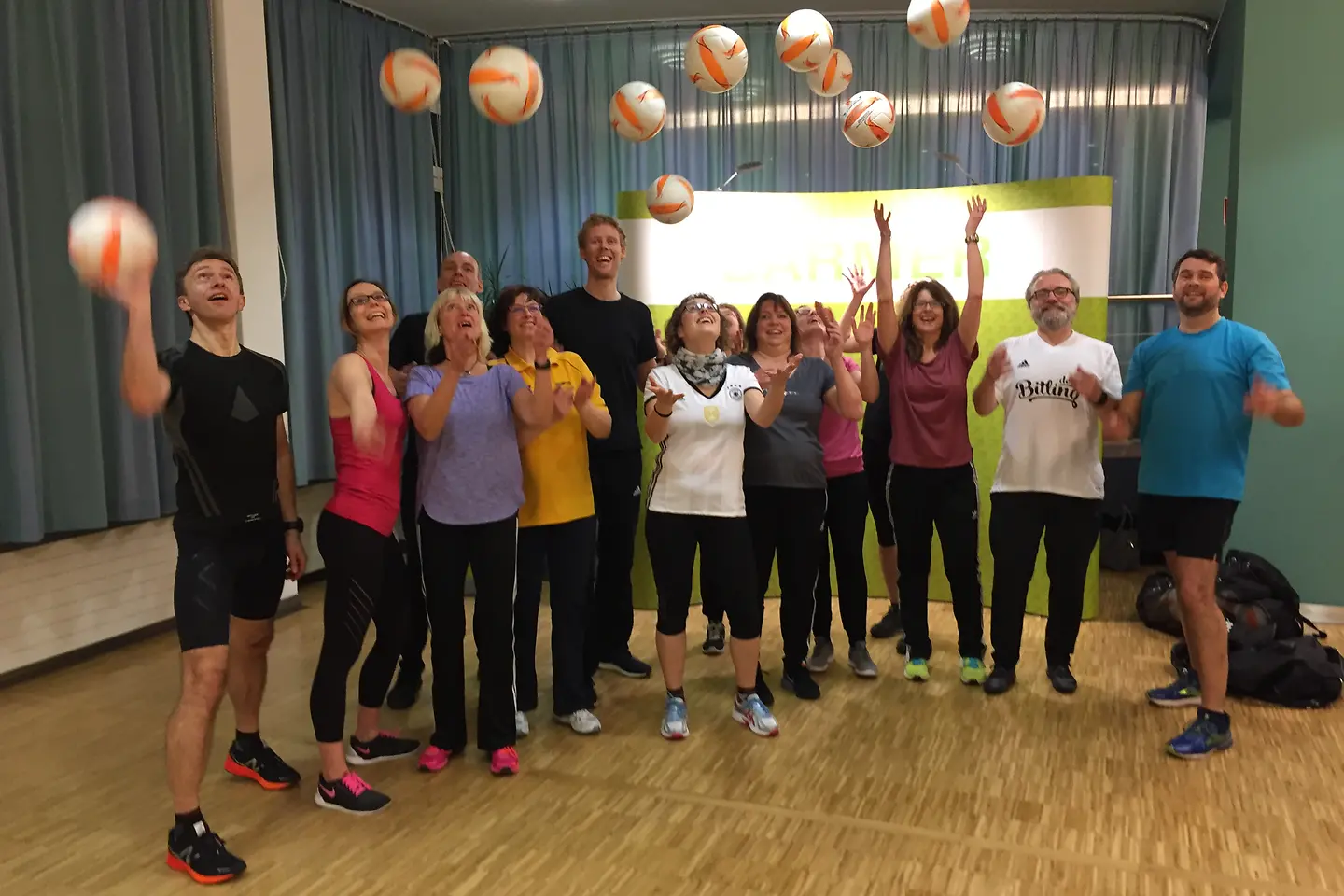 Jonas Reckermann wirft mit Sparkassenmitarbeitern Volleybälle in die Luft.