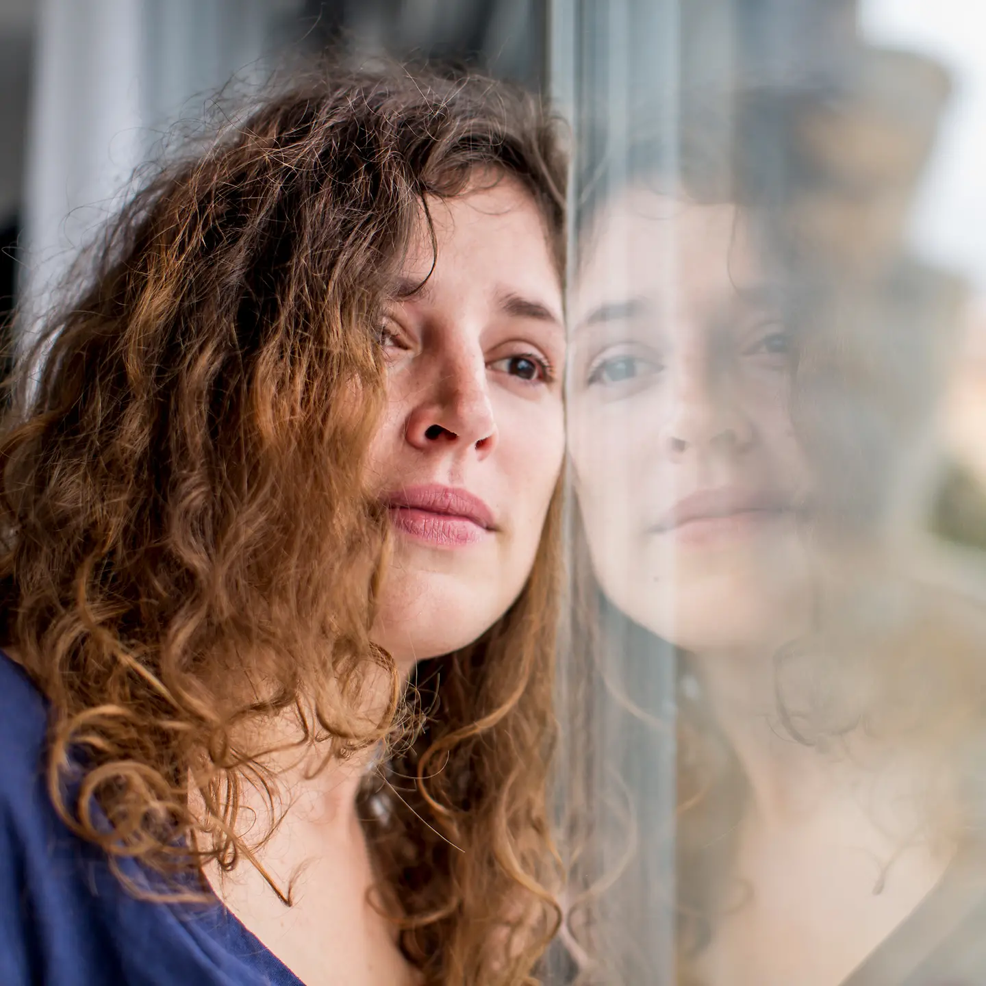 Frau schaut traurig aus dem Fenster