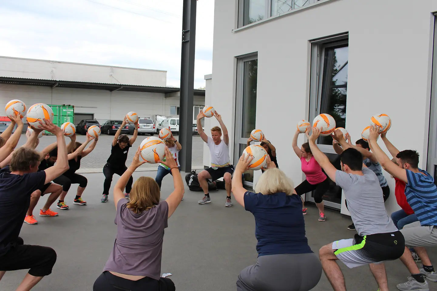 Jonas Reckermann wärmt Mitarbeiter von JF Hillebrand mit Beachvolleyball-Übungen auf.