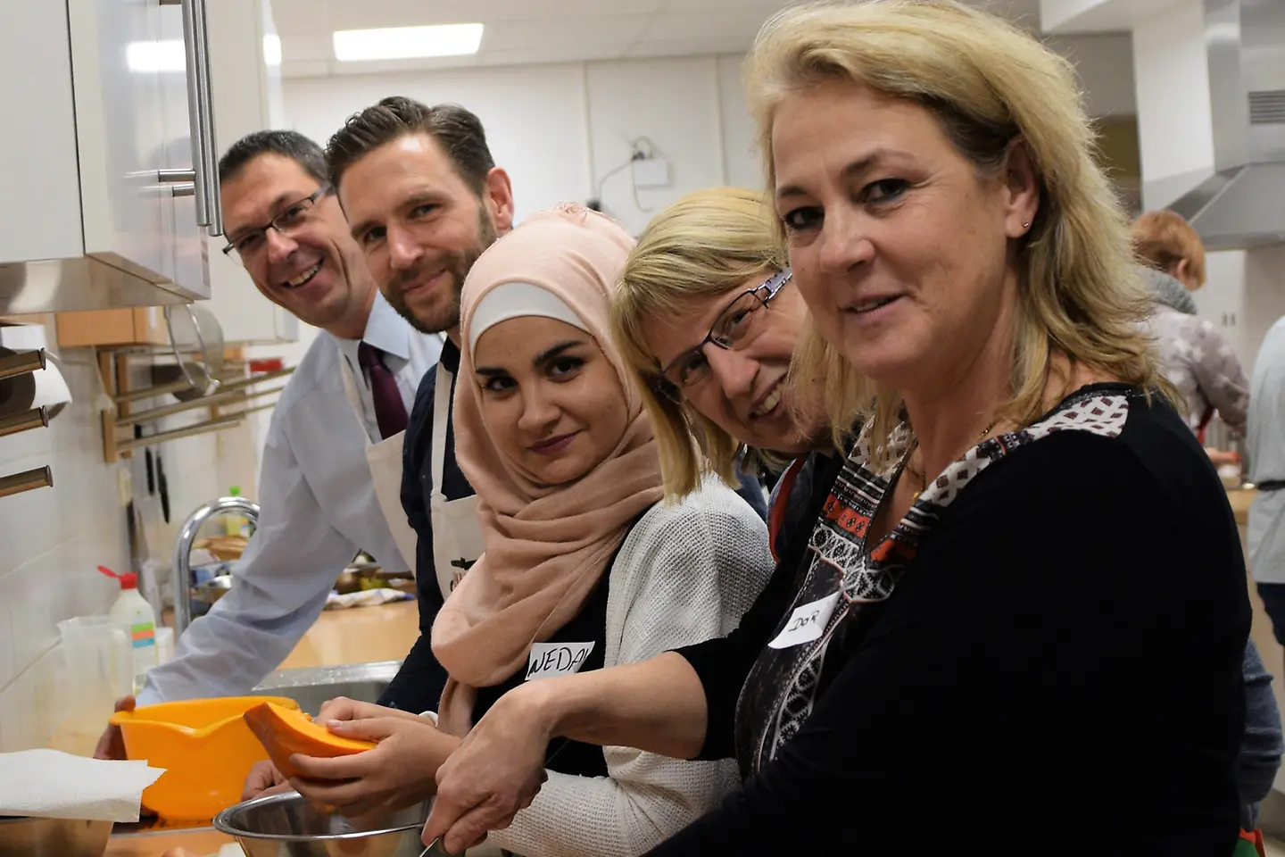 Angehende Genussbotschafterinnen schnippeln einen Kürbis mit Trainer Brandel und Barmer-Mitarbeiter.